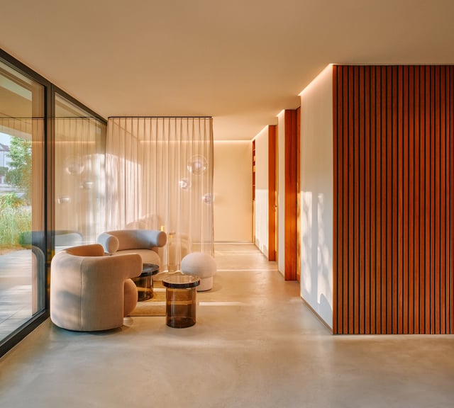 Sunlit clinic waiting area with curved armchairs, sheer curtains and a timber slatted wall