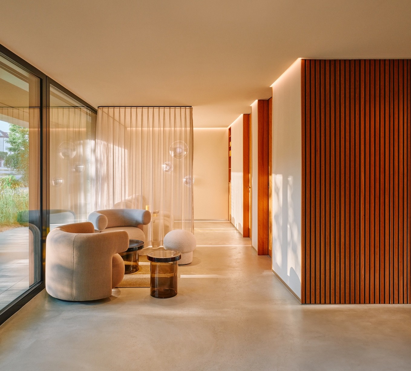 Sunlit clinic waiting area with curved armchairs, sheer curtains and a timber slatted wall